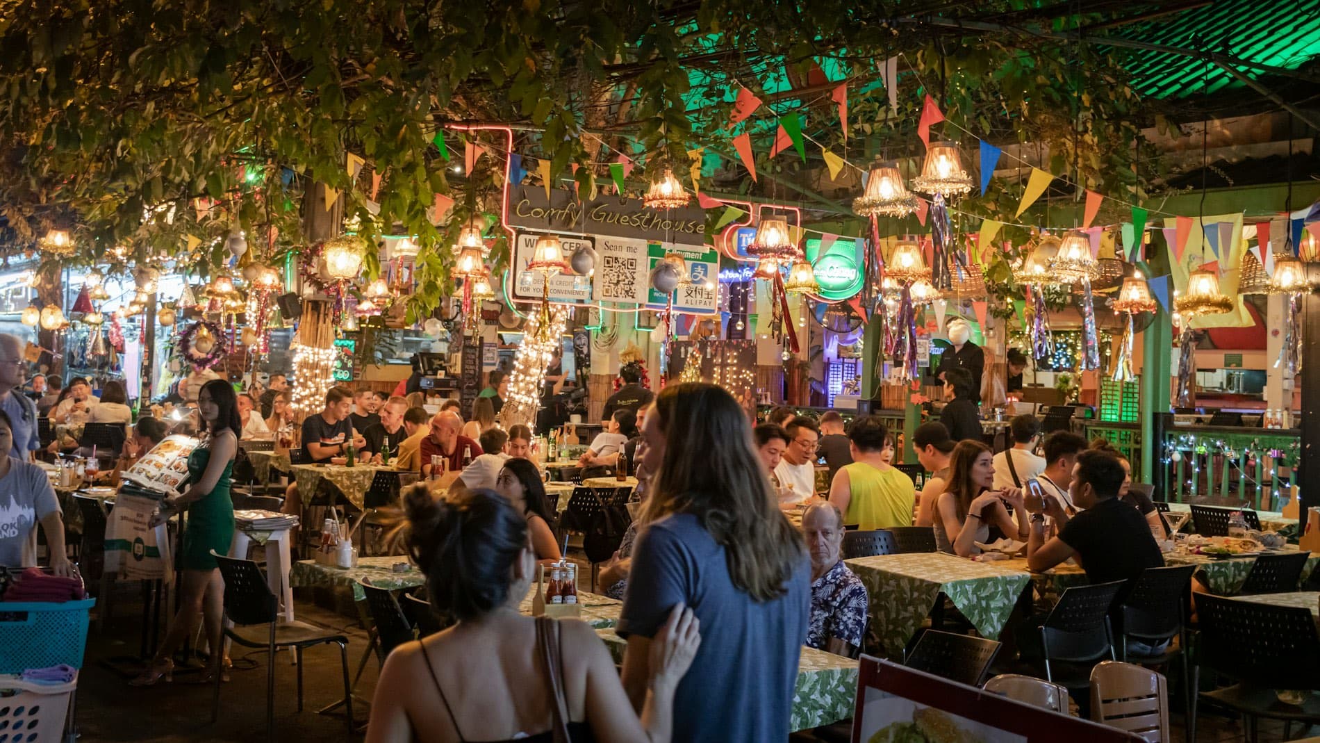 A restaurant patio full of guests under string lights